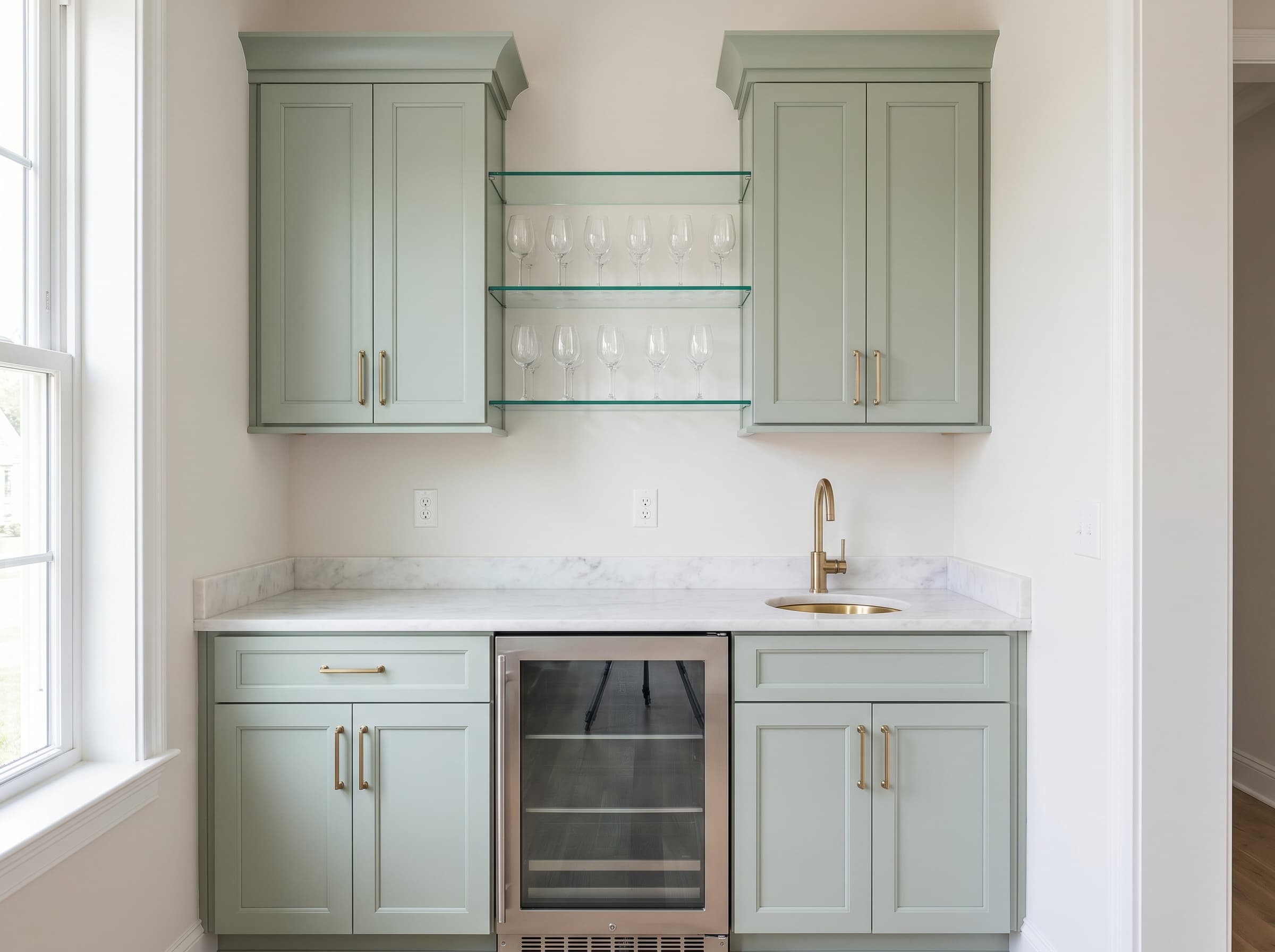 Sandy Springs, GA · Sage shaker wet bar with marble counter and glass stemware shelves.